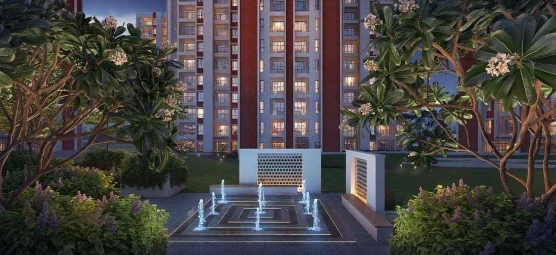 Evening view of landscaped garden with illuminated water fountain feature at DTC Capital City Crest, with residential towers in the background.